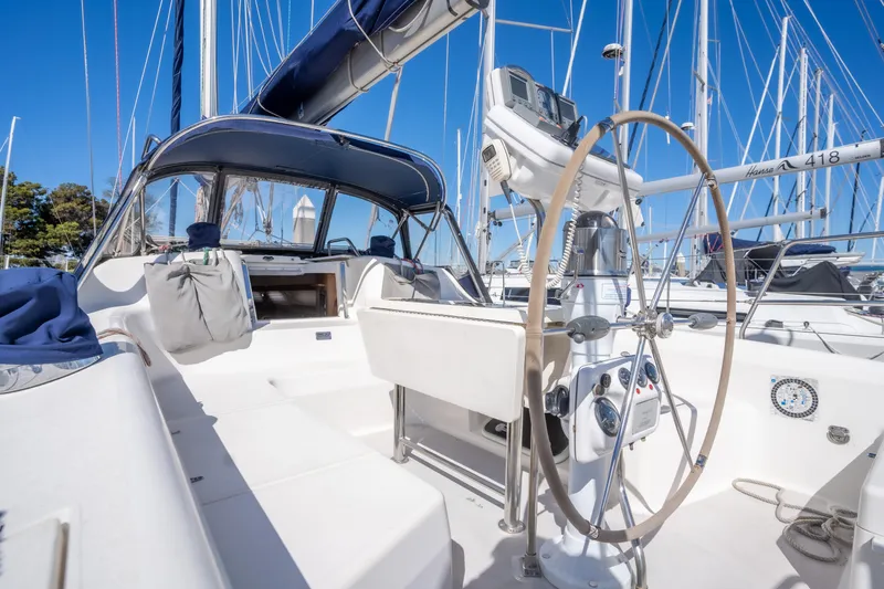 Aries Yacht Photos Pics 2002 Catalina 380 sailboat cockpit with steering wheel, docked in marina under clear blue sky.