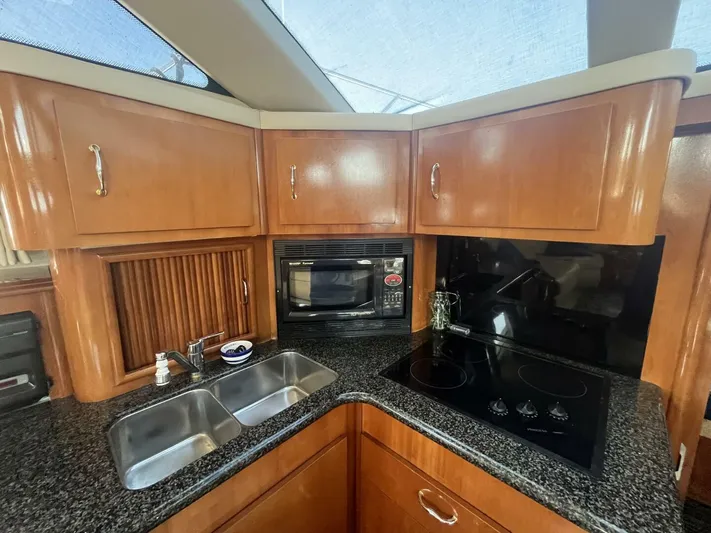  Yacht Photos Pics 2003 Carver 444 Cockpit Motor Yacht kitchen with wood cabinets, stove, microwave, and double sink.
