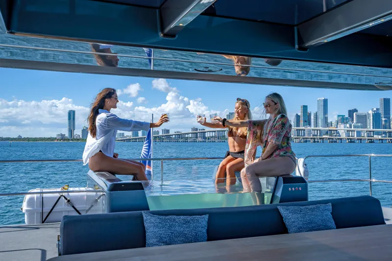 Skip The Wait - Trade Ins Considered Yacht Photos Pics Women enjoying drinks on a 2026 Sunreef 60 Power yacht with city skyline backdrop.