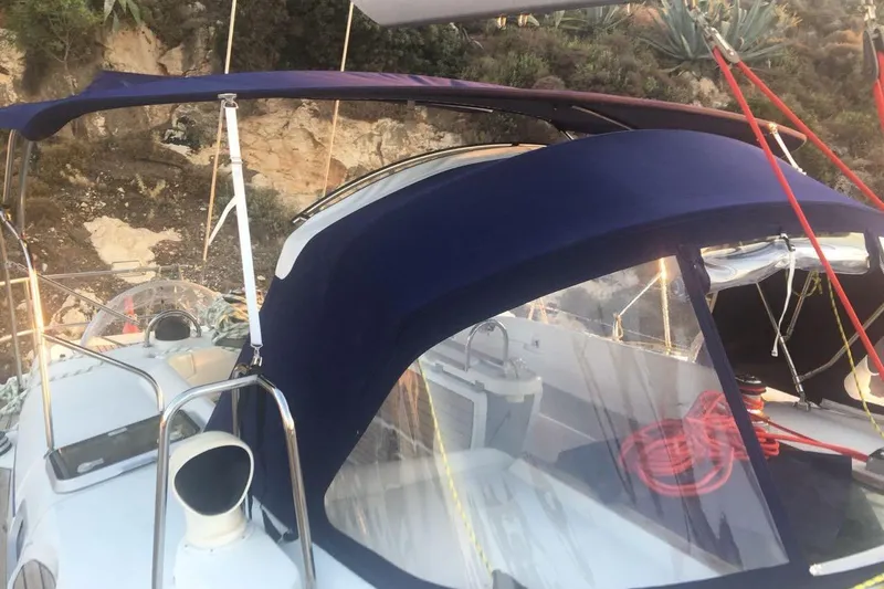  Yacht Photos Pics 1996 Beneteau 50 sailboat with blue canvas cover, docked near rocky shoreline.