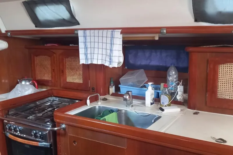  Yacht Photos Pics Galley kitchen in 1996 Beneteau 50 sailboat with stove, sink, and wooden cabinets.