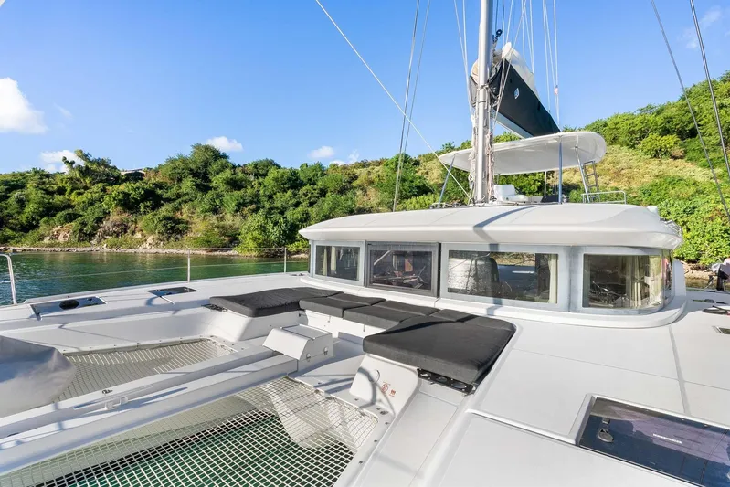 Echo Yacht Photos Pics 2023 Lagoon 50 catamaran with spacious deck, anchored near lush green shoreline.