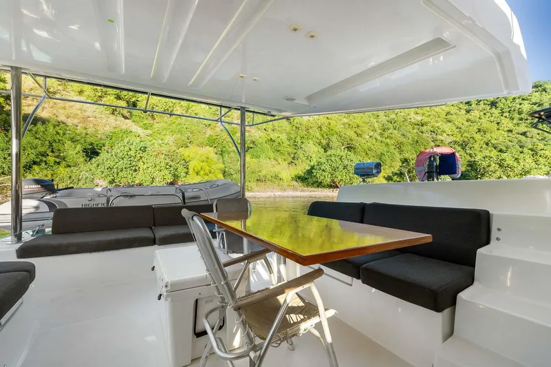 Echo Yacht Photos Pics 2023 Lagoon 50 yacht interior with seating and table, surrounded by lush greenery.