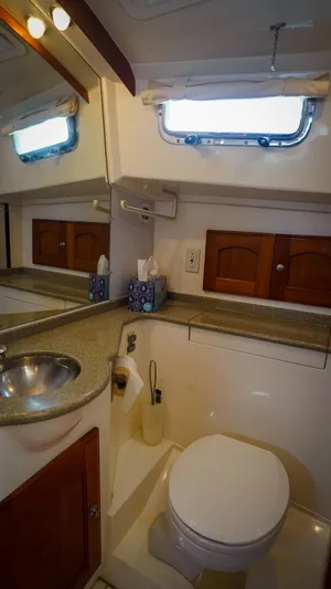 Gyspy Baby Yacht Photos Pics Compact bathroom in 2007 Legacy 32 boat with sink, toilet, and wooden cabinets.