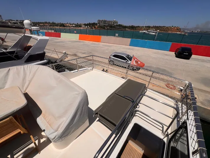 Yacht Photos Pics Deck view of 2018 Absolute 52 Navetta yacht docked near colorful barriers.