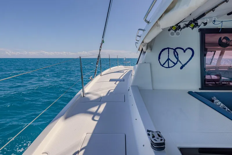 Happy Here Yacht Photos Pics 2020 Fountaine Pajot Saona 47 sailing on clear blue ocean, peace and heart symbols visible.