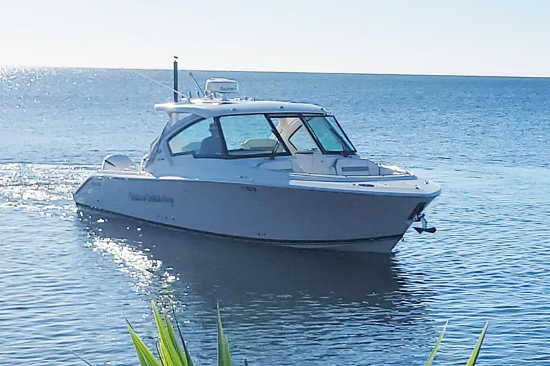  Yacht Photos Pics 2021 Pursuit DC 326 Dual Console boat cruising on calm ocean waters.