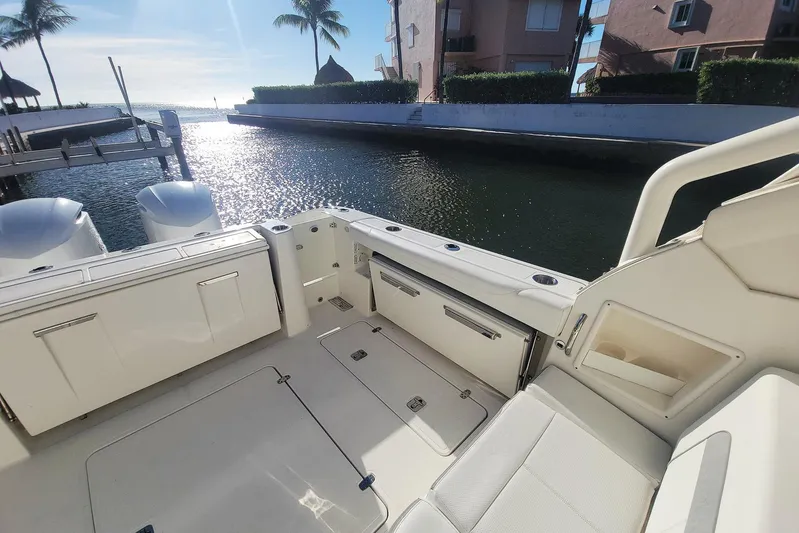 Yacht Photos Pics 2021 Pursuit DC 326 Dual Console boat interior with waterfront view, palm trees, and sunny sky.