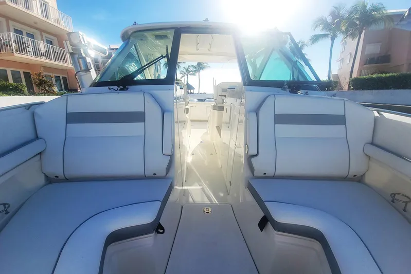  Yacht Photos Pics 2021 Pursuit DC 326 Dual Console boat interior with seating, sunny day, palm trees in background.