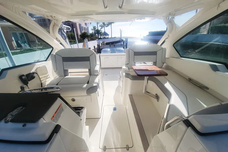  Yacht Photos Pics 2021 Pursuit DC 326 Dual Console boat interior with seating and table, docked by waterfront.