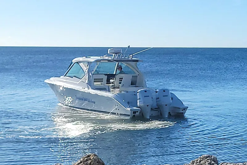  Yacht Photos Pics 2021 Pursuit DC 326 Dual Console boat cruising on calm ocean waters.