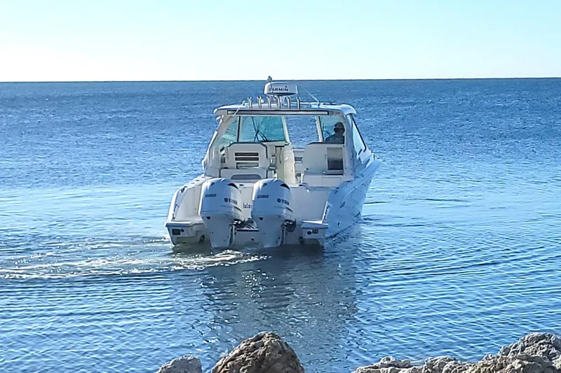  Yacht Photos Pics 2021 Pursuit DC 326 Dual Console boat cruising on calm ocean waters.