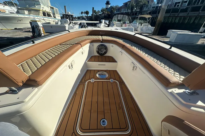 O-sea-d 2 Yacht Photos Pics 2021 Scout 251 XSS boat interior with tan seating and wood flooring at a marina.