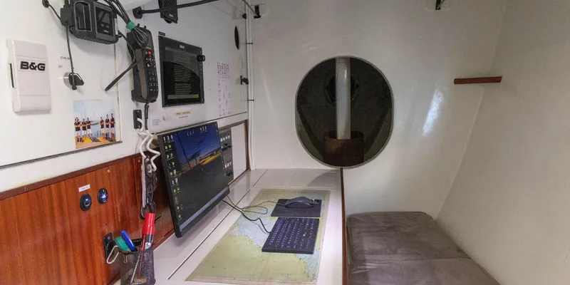 Maxicat Victoria Yacht Photos Pics Navigation station inside 2000 Multiplast Maxi Catamaran, featuring computer, maps, and communication equipment.