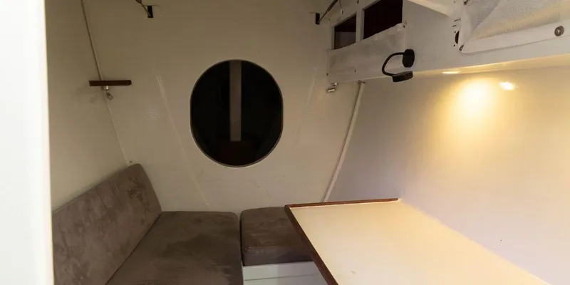 Maxicat Victoria Yacht Photos Pics Interior of 2000 Multiplast Maxi Catamaran with seating, table, and round window.