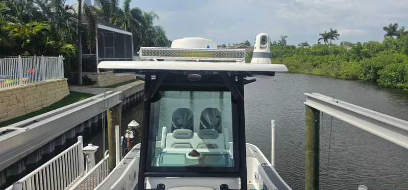  Yacht Photos Pics 2023 Caymas 28 HB Twin boat docked by a canal with lush greenery.