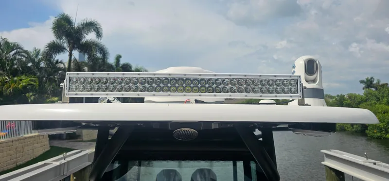  Yacht Photos Pics 2023 Caymas 28 HB Twin boat with LED light bar, docked near tropical foliage.