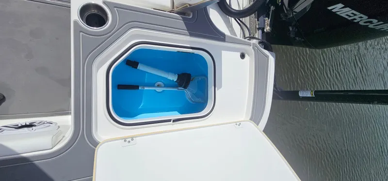  Yacht Photos Pics 2023 Caymas 28 HB Twin boat storage compartment with cleaning brush, docked by water.