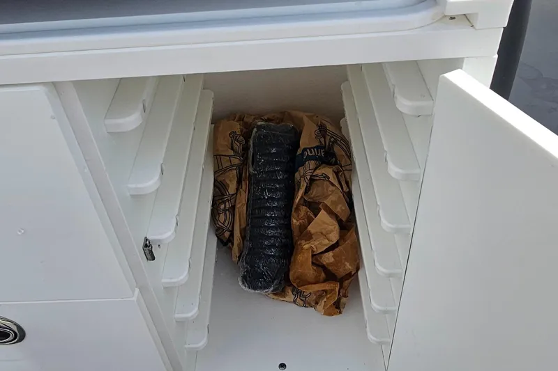  Yacht Photos Pics Open storage compartment in 2023 Caymas 28 HB Twin boat, containing wrapped items.