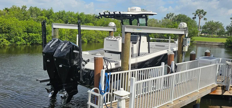  Yacht Photos Pics 2023 Caymas 28 HB Twin boat docked with dual Mercury engines, surrounded by lush greenery.