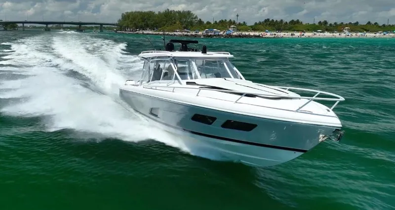  Yacht Photos Pics 2021 Intrepid 409 Valor cruising on vibrant green water near a scenic shoreline.