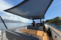Fjord 40 Open 2020 yacht with shaded deck, scenic coastal view.