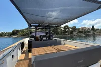 Fjord 40 Open 2020 yacht with sunshade, docked near scenic coastline.