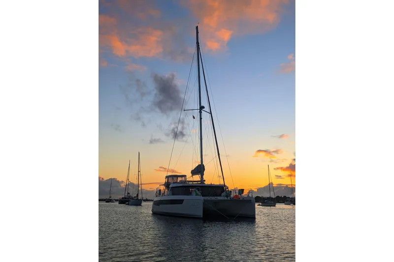 Momentum 42 Yacht Photos Pics 2023 Leopard 42 catamaran at sunset, anchored in a tranquil harbor.