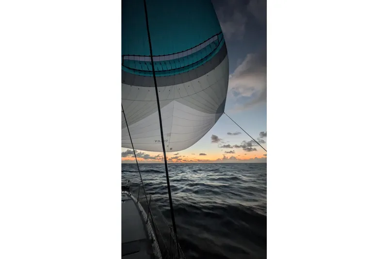 Momentum 42 Yacht Photos Pics Sailing at sunset on a 2023 Leopard 42 catamaran, vibrant spinnaker against ocean waves.