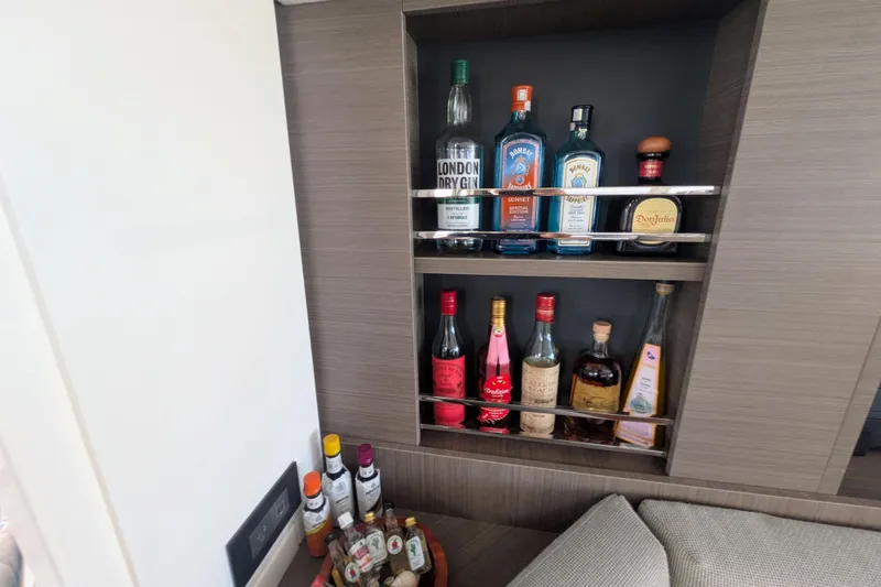 Momentum 42 Yacht Photos Pics Bar area on Leopard 42 yacht, showcasing assorted liquor bottles in a modern wooden cabinet.