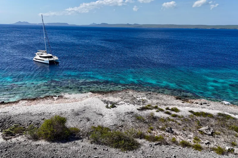 Momentum 42 Yacht Photos Pics Sailboat Leopard 42 anchored near rocky shore with clear blue ocean, 2023.