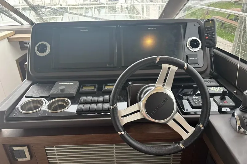 Improbable Yacht Photos Pics Control panel of a 2019 Prestige 520 yacht with steering wheel and navigation screens.