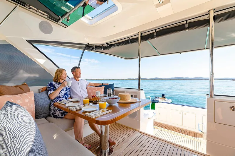  Yacht Photos Pics Manufacturer Provided Image: Couple enjoying breakfast on 2025 Riviera 585 SUV yacht, overlooking serene ocean view.