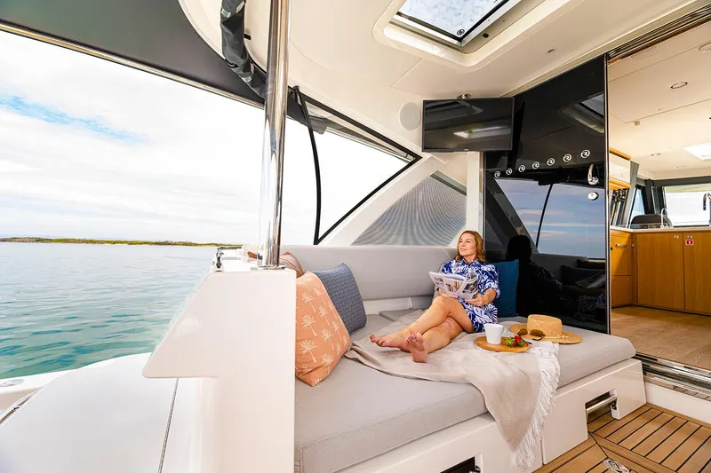  Yacht Photos Pics Manufacturer Provided Image: Woman relaxing on 2025 Riviera 585 SUV yacht, enjoying a serene ocean view.