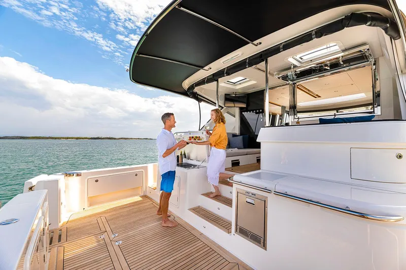  Yacht Photos Pics Manufacturer Provided Image: Couple enjoying leisure time on 2025 Riviera 585 SUV yacht deck.