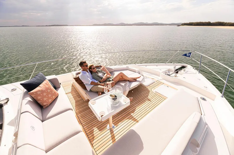 Yacht Photos Pics Manufacturer Provided Image: Couple relaxing on 2025 Riviera 585 SUV yacht deck, enjoying serene ocean view.