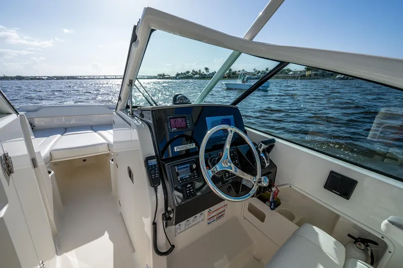  Yacht Photos Pics 2021 Pursuit DC 266 Dual Console boat interior with steering wheel and control panel, overlooking water.
