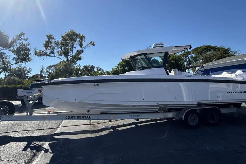  Yacht Photos Pics 2025 Axopar 29 CCX boat on trailer, parked outdoors under clear blue sky.