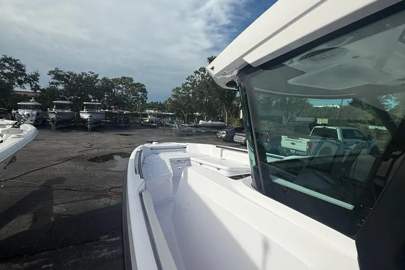  Yacht Photos Pics 2025 Axopar 29 CCX boat in a marina, surrounded by parked vehicles and trees.