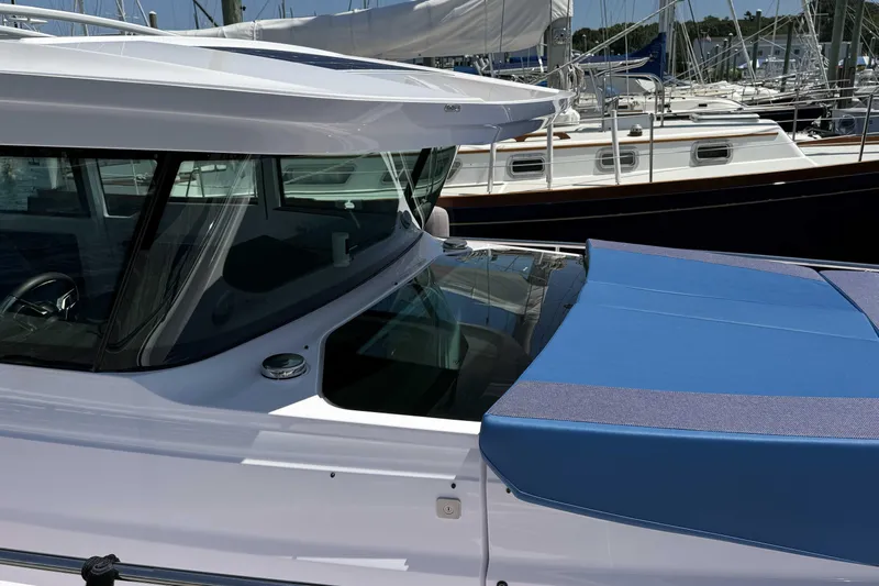  Yacht Photos Pics 2024 Axopar 37 XC CROSS CABIN boat with sleek design and blue cover in marina.