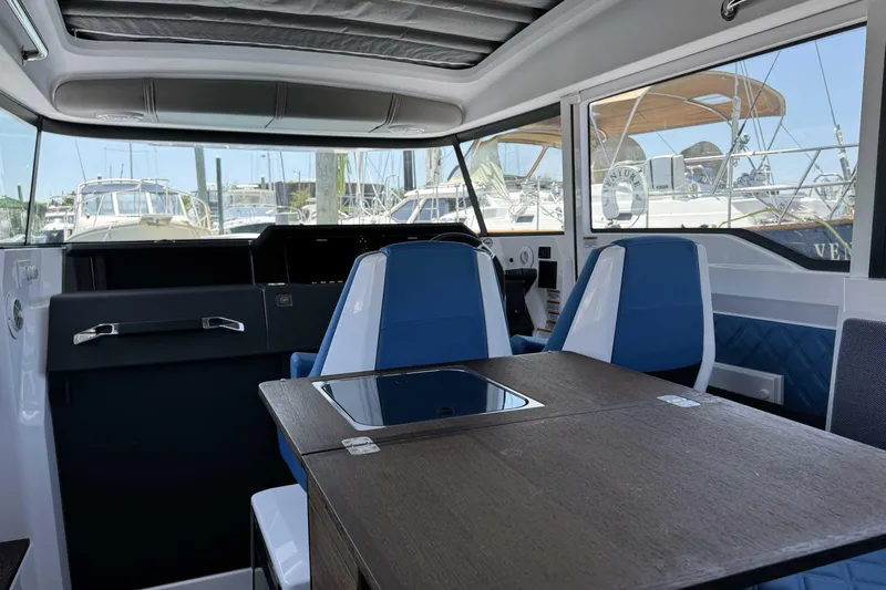  Yacht Photos Pics 2024 Axopar 37 XC CROSS CABIN interior with blue seating and wooden table.