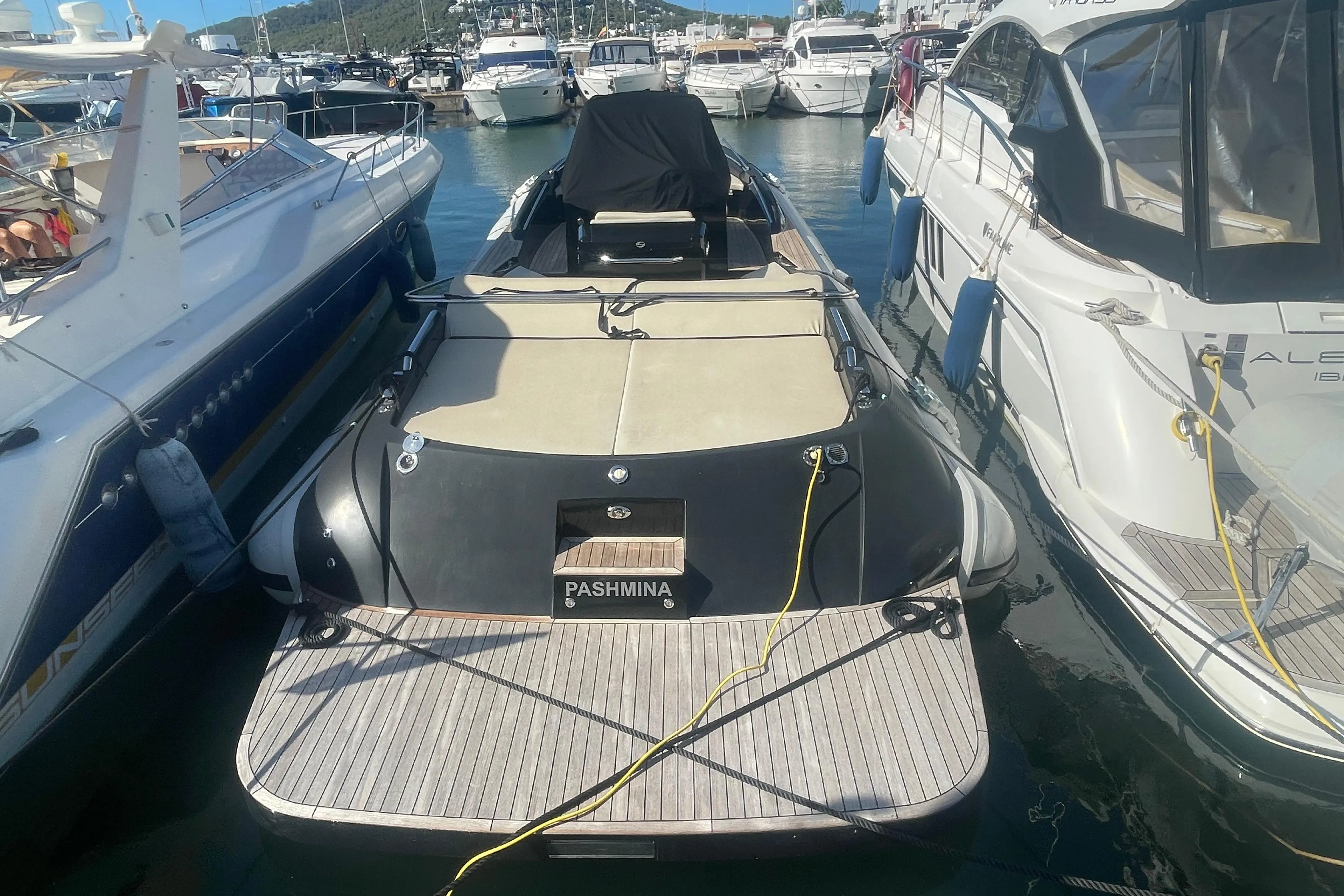Luxury yacht docked in marina, surrounded by other boats, sunny day.