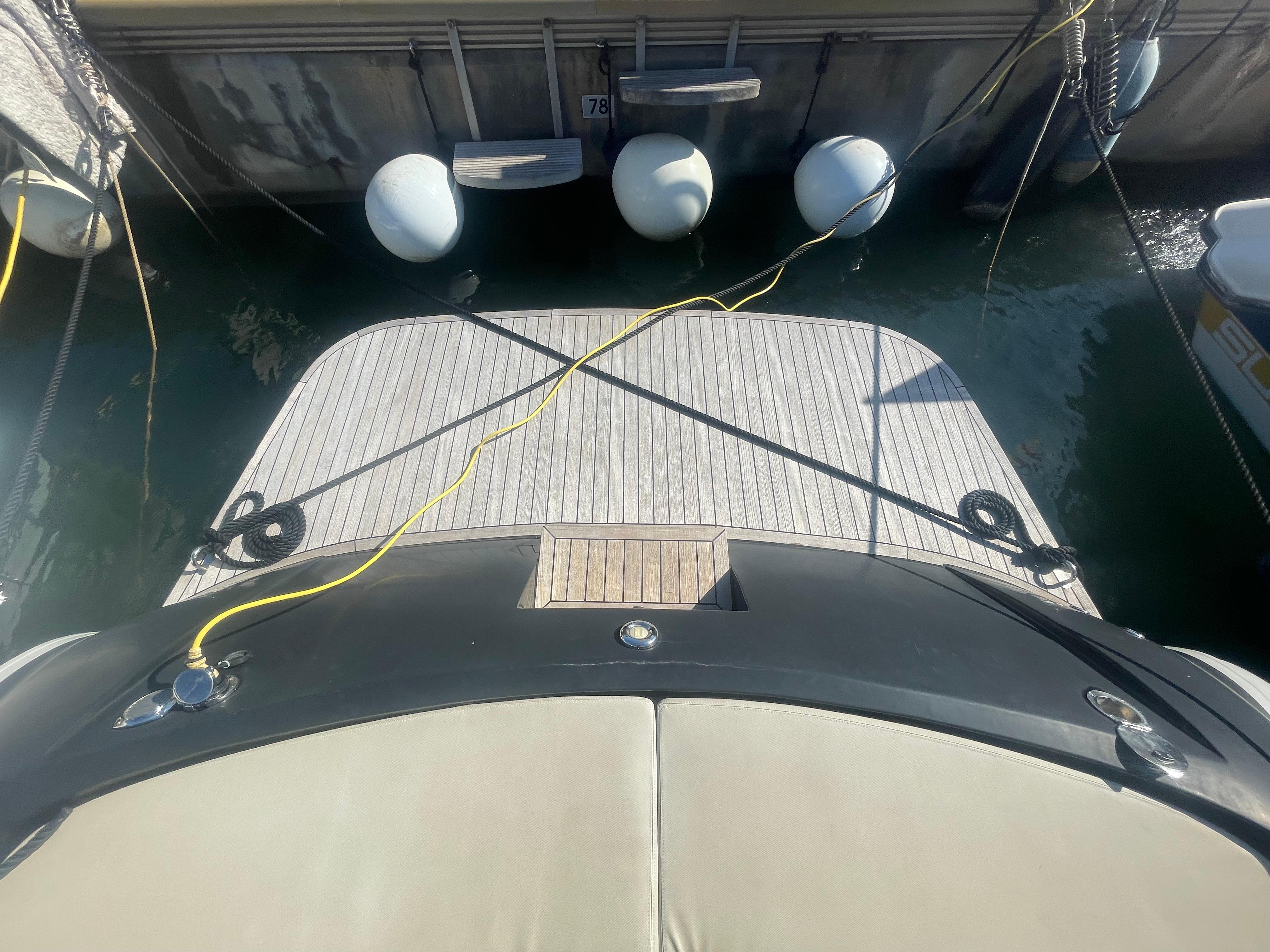 Boat docked with fenders and power cables, viewed from above.