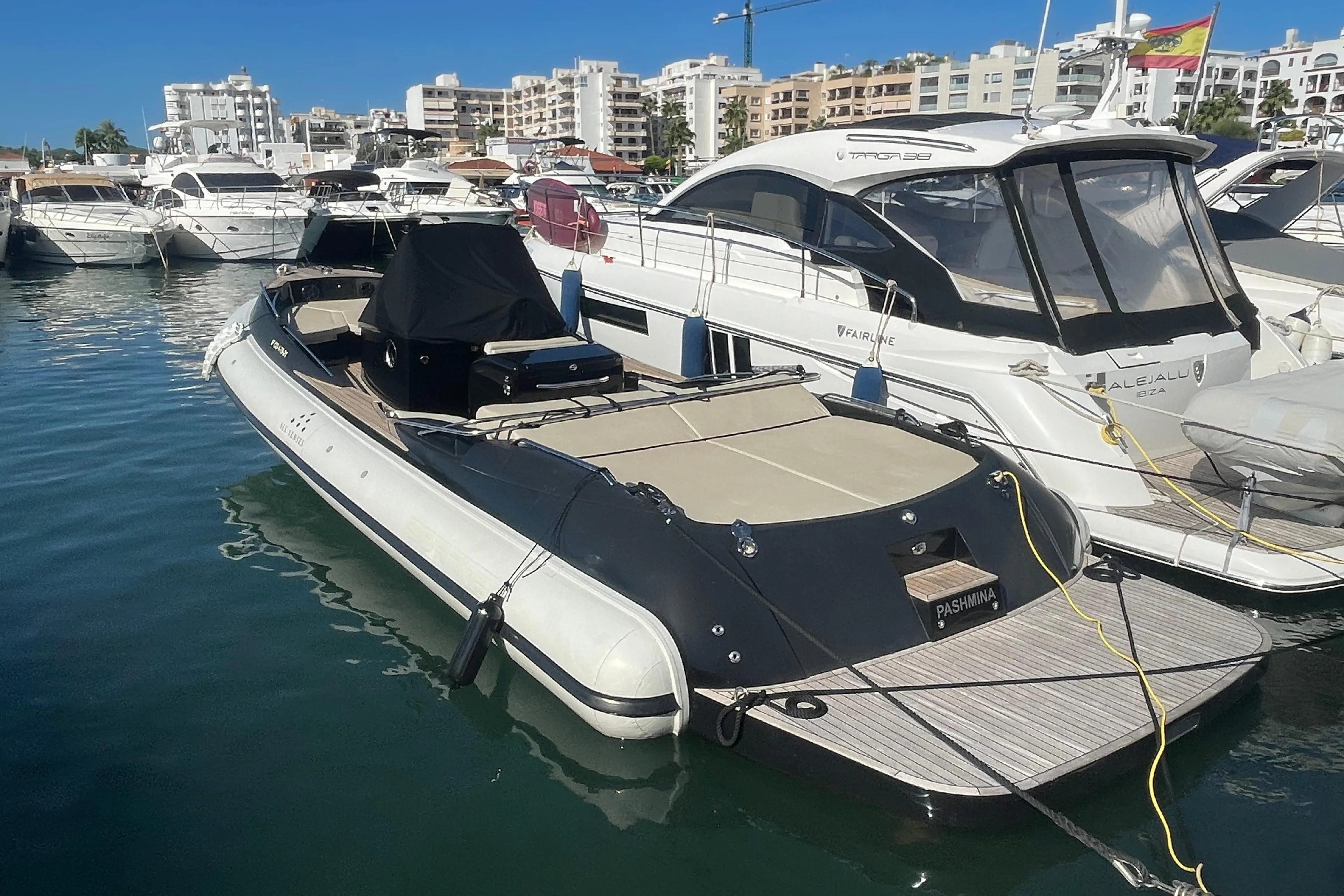 Luxury Scanner Envy 950 boat docked in marina, surrounded by other yachts, sunny day.