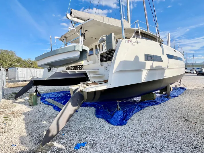Windsurfer Yacht Photos Pics 2022 Max Cruise Marine 44SC catamaran on land, blue tarp underneath, clear sky background.