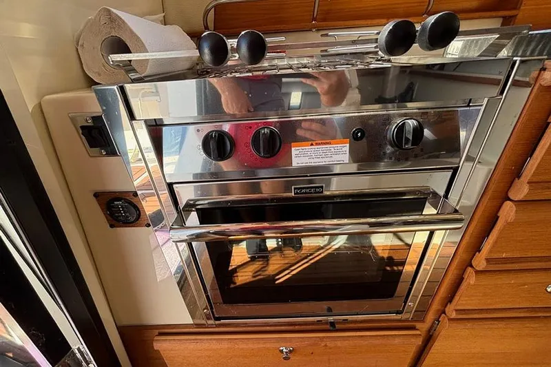  Yacht Photos Pics 2021 Ranger Tugs R-27 kitchen with stainless steel oven and wooden cabinetry.