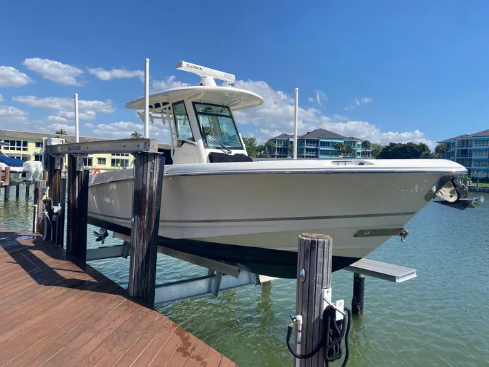  Yacht Photos Pics 2020 Boston Whaler 280 Outrage boat docked on lift, sunny day, waterfront homes in background.