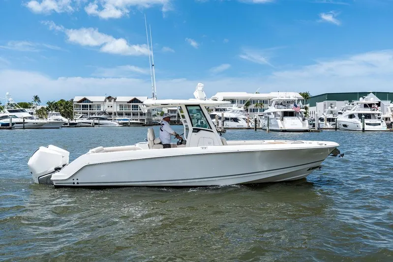  Yacht Photos Pics 2020 Boston Whaler 280 Outrage boat cruising in a marina under a clear blue sky.