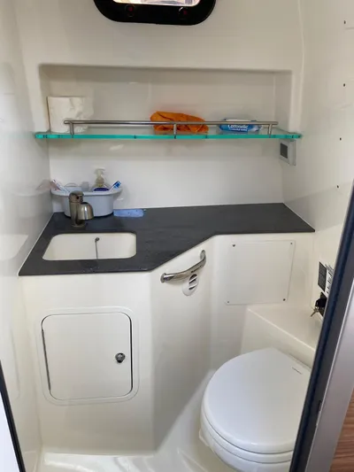  Yacht Photos Pics 2021 Boston Whaler 325 Conquest bathroom with sink, toilet, and storage shelf.