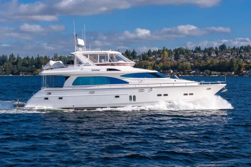 Wishlist Yacht Photos Pics Luxurious 2009 Horizon 73 yacht cruising on a scenic lake under a partly cloudy sky.